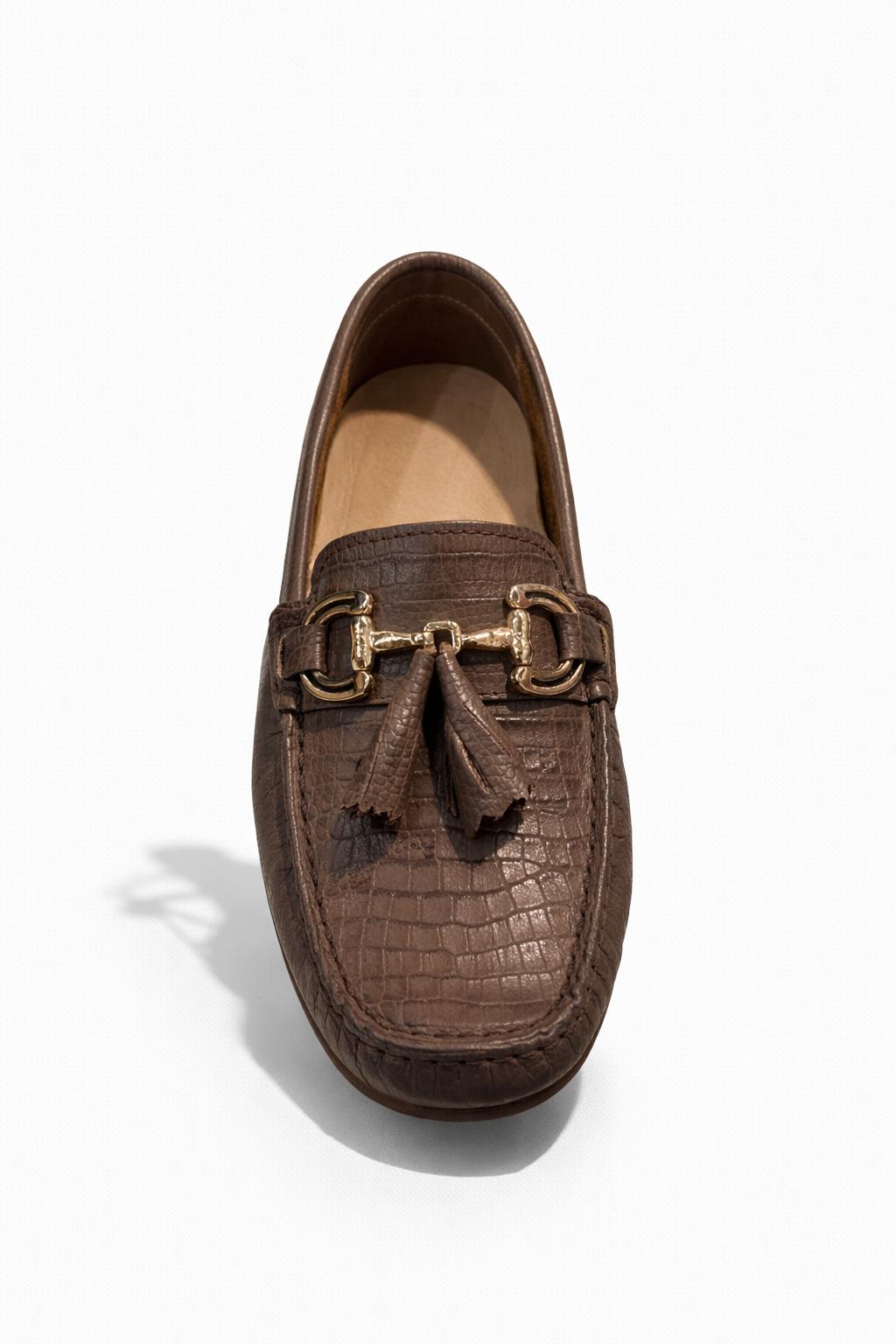 Mocasín café con textura grabada y borlas decorativas