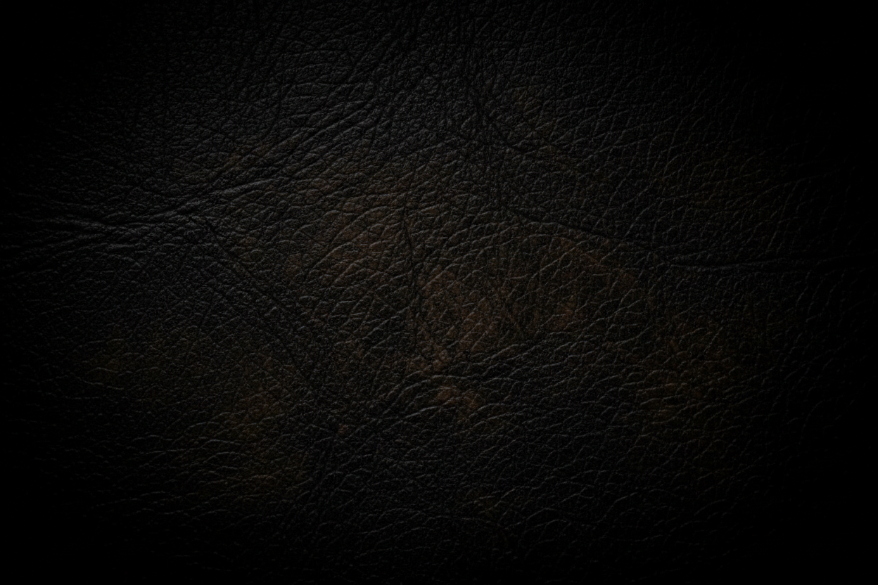 Fondo de pantalla abstracto y elegante de cuero genuino negro y marrón oscuro con una iluminación dramática y tenue. Primer plano macro de la textura del grano de piel premium. Estilo minimalista, lujoso y sofisticado. Sin objetos, solo textura y sombras profundas. Oscuro, casi negro en los bordes (viñeteado), perfecto para superponer texto blanco encima. Alta resolución, 8k, fotografía de producto de estudio.